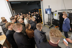 Grupa studentów obserwuje pokaz technologiczny przy stanowisku obróbkowym w hali produkcyjnej,